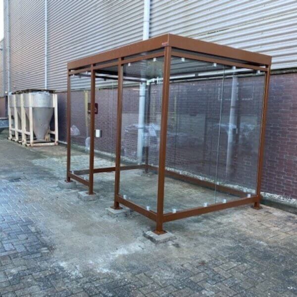 Rokersruimte in cortenstaal-look met glazen wanden, geplaatst op betonpoeren voor een waterpas en stabiele fundering.