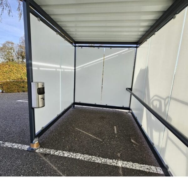 Rookabri met leunbeugel en wandasbak kopen Interieur van een rookabri met glazen wanden voorzien van zeefdruk, een zwarte leunbeugel en een RVS wandasbak aan de zijkant.