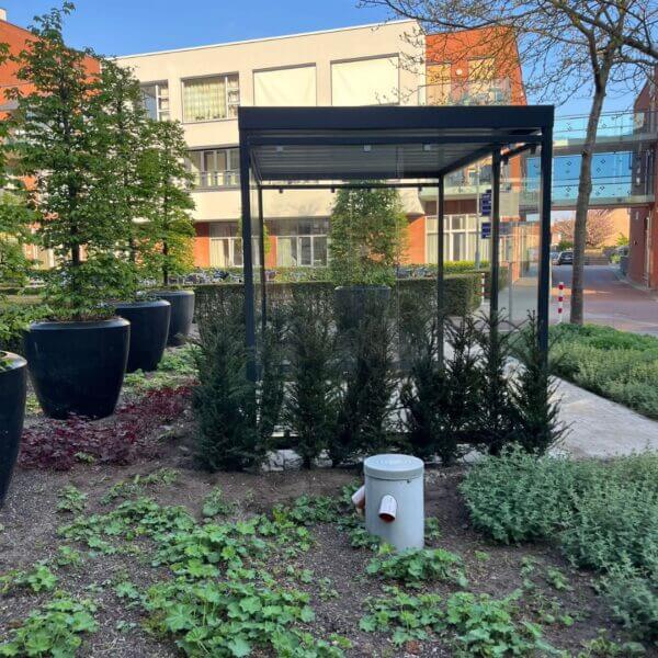 rookabri voor senioren kopen van glas Rookabri met glazen wanden geplaatst in groene binnentuin bij appartementencomplex