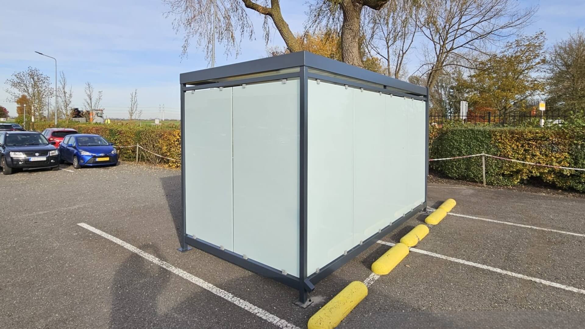 Rookoverkapping van Umfeldt met glazen zijwanden en zeefdruk, geplaatst op de parkeerplaats bij Friesland Campina in Bedum.
