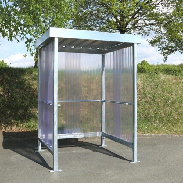 Verzinkte rookabri met polycarbonaat zij- en achterwanden Verzinkte rookabri met polycarbonaat zij- en achterwanden, geplaatst op asfalt bij groenvoorziening
