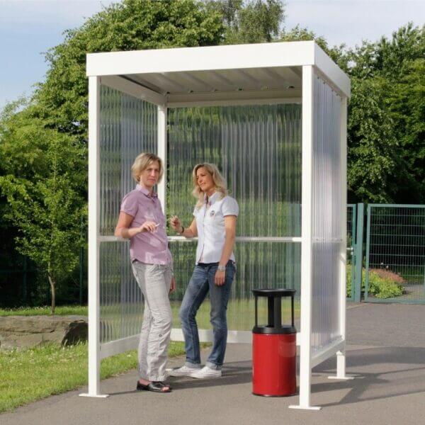 rokersabri kopen voor 2-3 personen Rookabri in RAL-9002 met polycarbonaat zij- en achterwanden, gebruikt door twee vrouwen met een rode en zwarte asbak