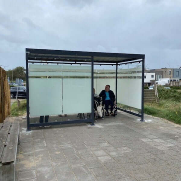 Rolstoel vriendelijke rookabri online bestellen Rookabri met ESG glazen wanden en optionele zeefdruk, toegankelijk voor mindervaliden en rolstoelgebruikers.