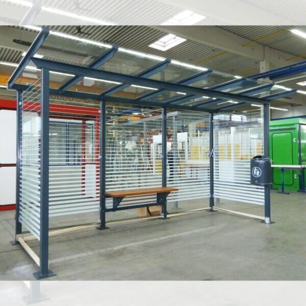 Rookabri en bushokje met ESG glas en zeefdruk, optionele zitbank en prullenbak, leverbaar in diverse RAL-kleuren en lengtes.