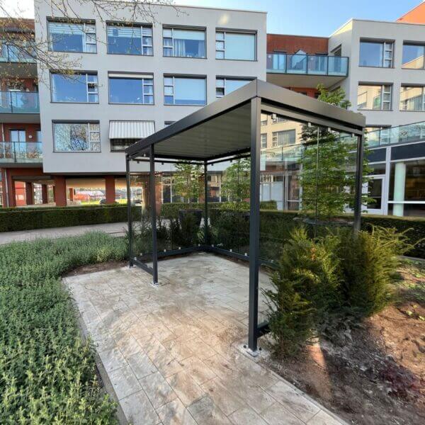 rookoverkapping umfeldt aanschaffen Rookoverkapping met glazen wanden en modern stalen frame bij appartementencomplex