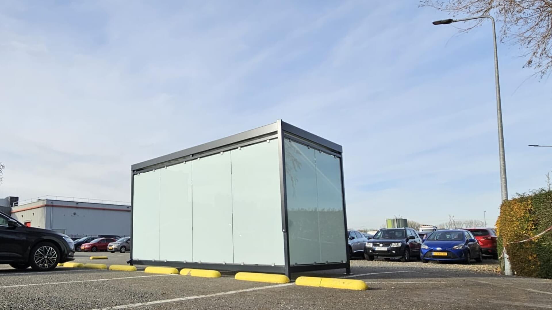 Vrijstaande rookoverkapping van Umfeldt met glazen wanden en zeefdruk, geplaatst op het parkeerterrein bij Friesland Campina in Bedum.