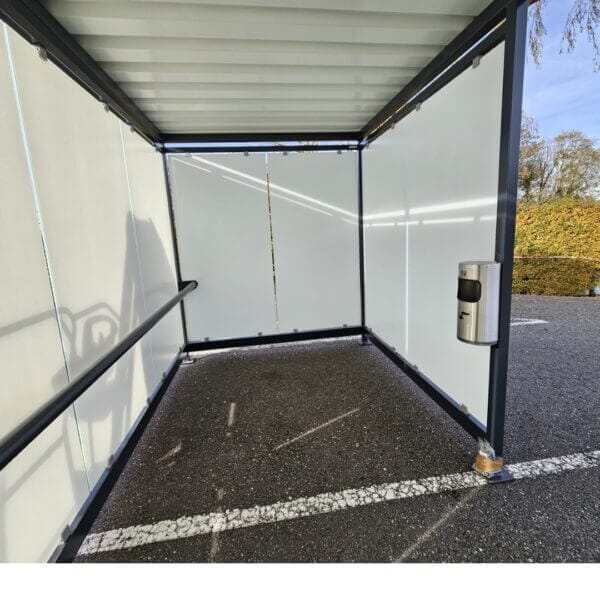 Rookruimte buiten met zeefdrukglas en wandasbak kopen Binnenkant van een rookruimte buiten met glazen wanden voorzien van zeefdruk, een zwarte leuning en een wandasbak van 10 liter.