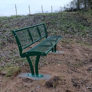 Groene stalen parkbank met rugleuning in RAL 6005 geplaatst op een zandstrook in een park in Wilp vervaardigd uit gegalvaniseerd staal en leverbaar in elke RAL-kleur voor wie een parkbank van staal wil bestellen.