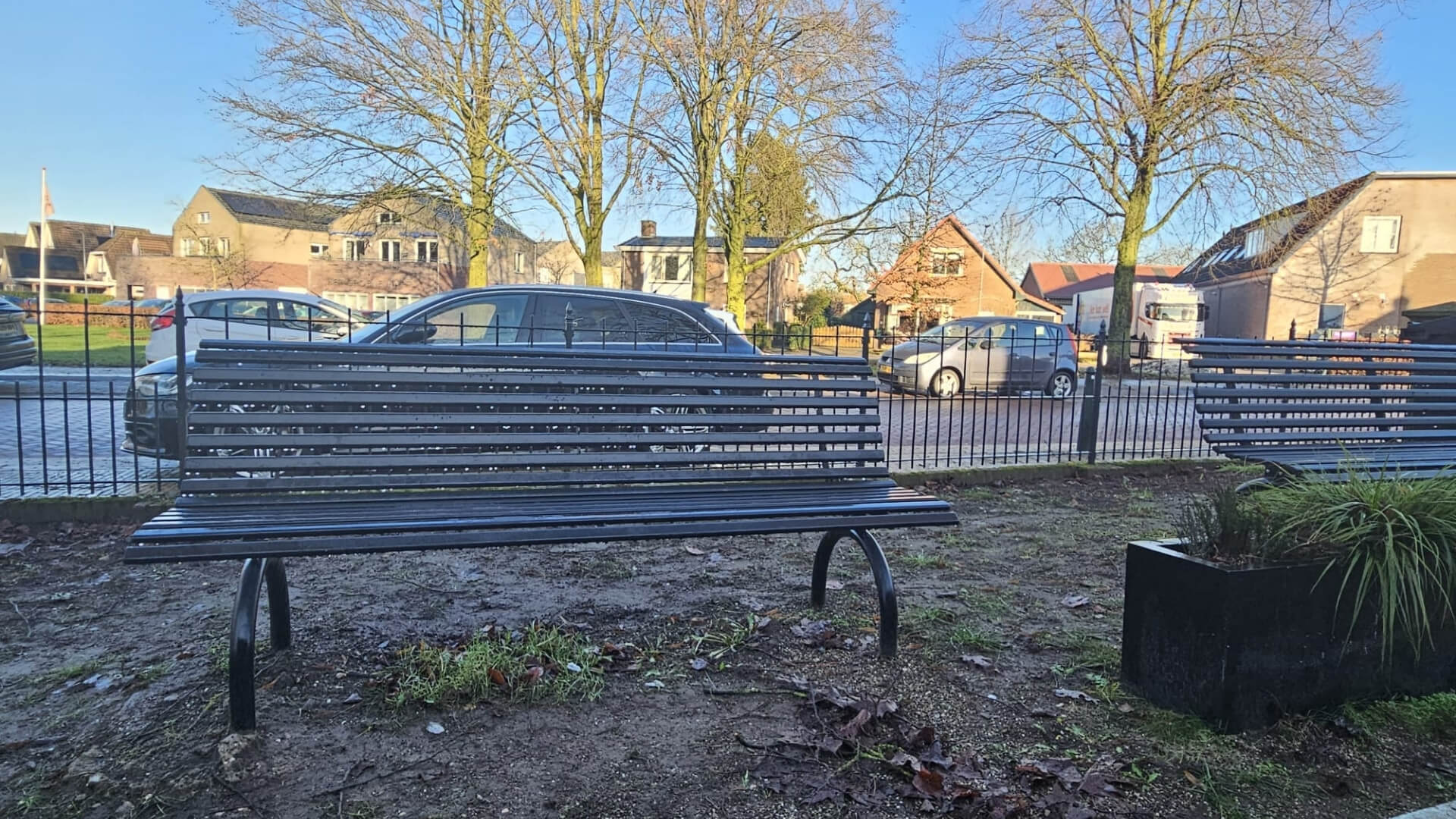 Buitenbank van staal in kleur zwart geplaatst in een dorp op een zonnige dag