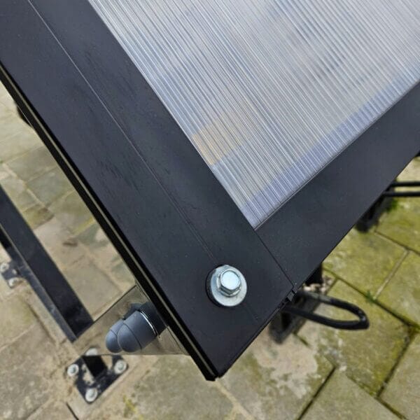 Fietsoverkapping detail zwart Marne Detail foto van fietsoverkapping Marne zwart, bevestigingsmechanisme van staal en polycarbonaat.