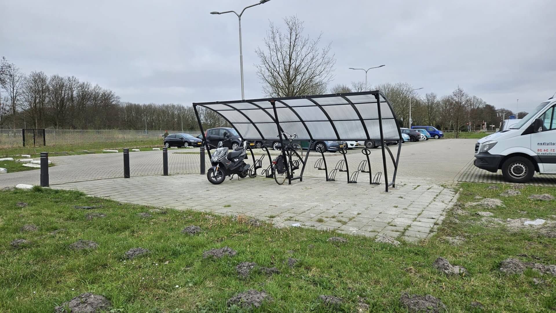 Fietsoverkapping van 5 meter in RAL 7016 geplaatst bij carpoolstrook in Woerden met gebogen polycarbonaat dak en meerdere fietsbeugels