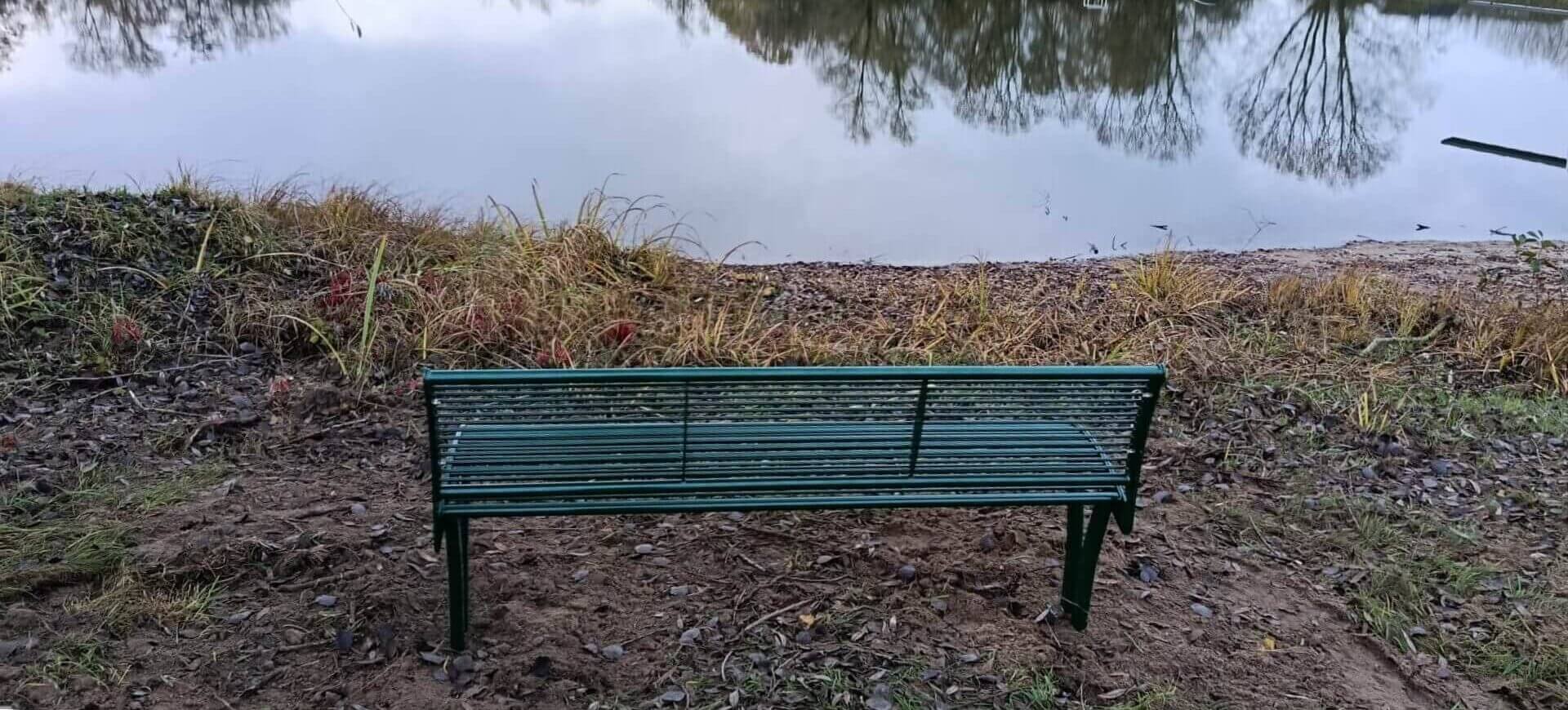 Groene Tauri parkbank van gegalvaniseerd staal in RAL 6005 aan de oever van een vijver in een park in Wilp leverbaar in elke RAL-kleur en ideaal voor organisaties die een parkbank van staal willen bestellen.