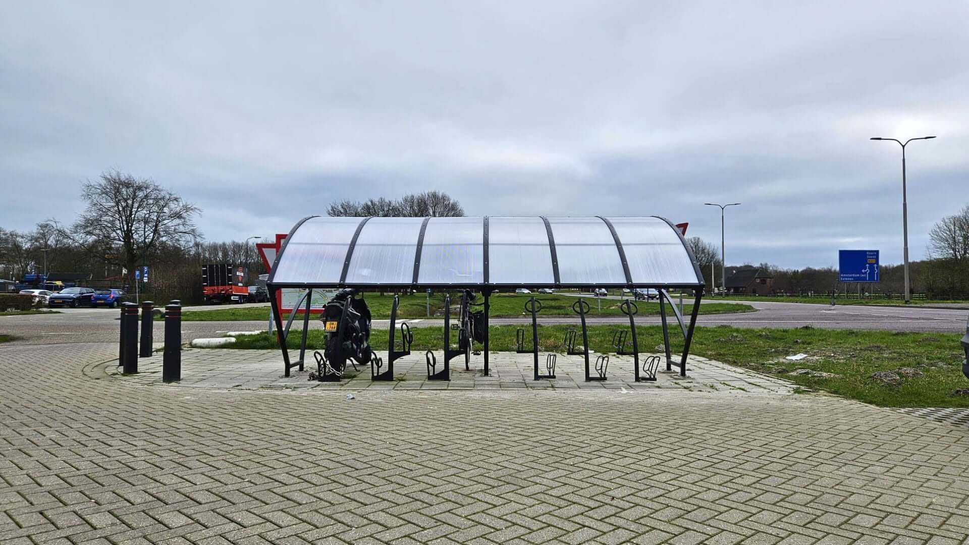 Fietsoverkapping van 5 meter in RAL 7016 geplaatst bij carpoolstrook in Woerden met gebogen polycarbonaat dak en fietsbeugels