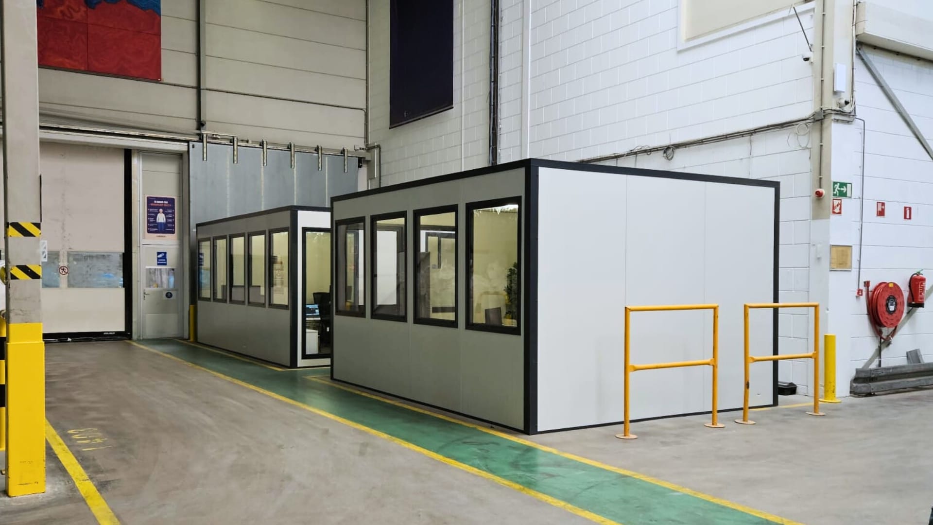 Kantoorunit Smart van Umfeldt met wit aluminium panelen en antraciet grijze kozijnen, gemonteerd in een productieomgeving