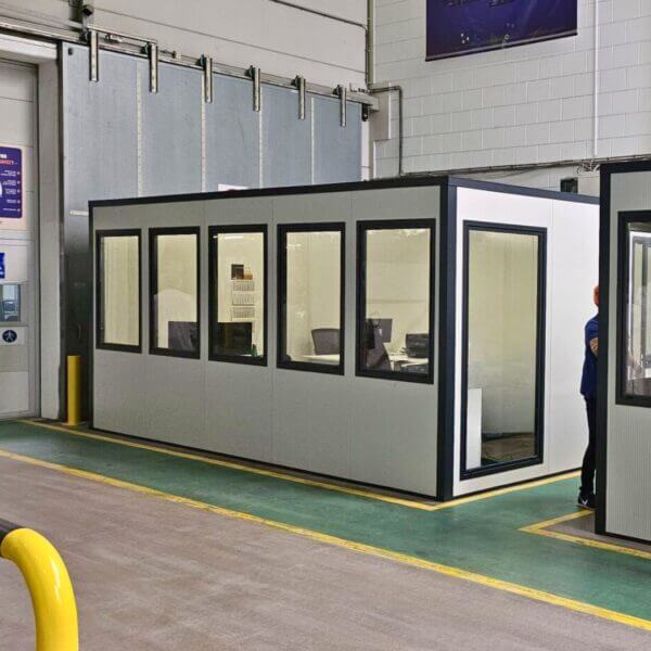 Mobiele kantoorunit kopen Mobiele kantoorunit met ramen, geplaatst in een productiehal voor afgeschermd en flexibel werken