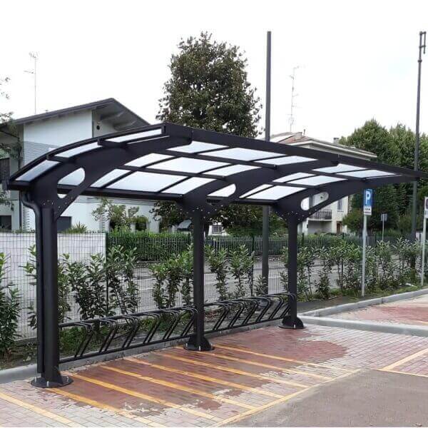 Fietsenstalling staal aanschaffen voor stations Stijlvolle fietsenstalling van staal met gebogen dak en fietsenrek op houten ondergrond.