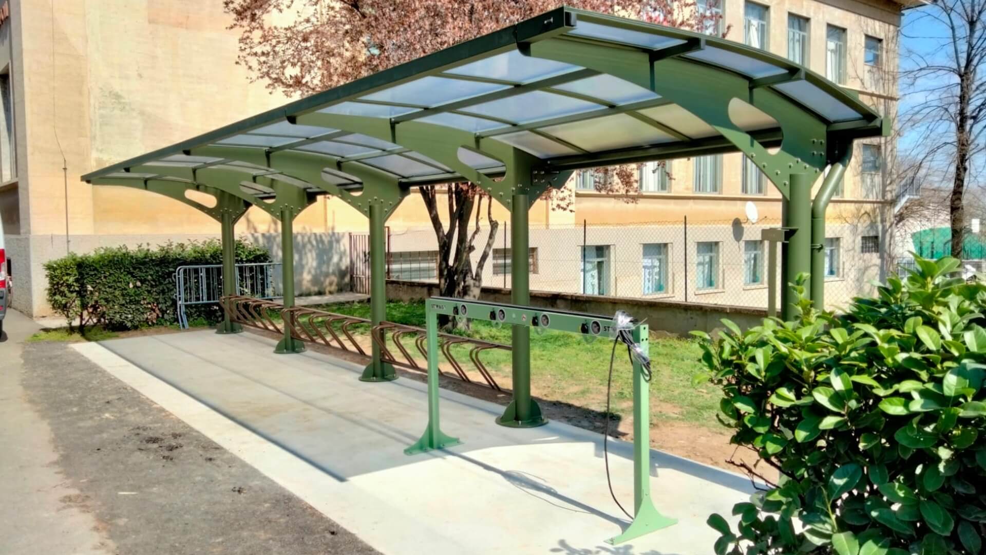 Rijwieloverkapping in kleur groen, geschikt voor het stallen van 20 fietsen, geplaatst naast een kantoor