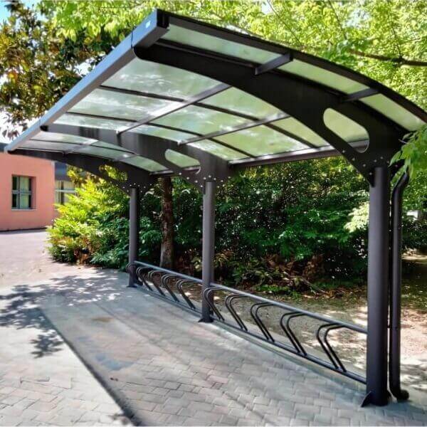 Moderne stalen fietsenoverkapping met gebogen dak en geïntegreerd fietsenrek.