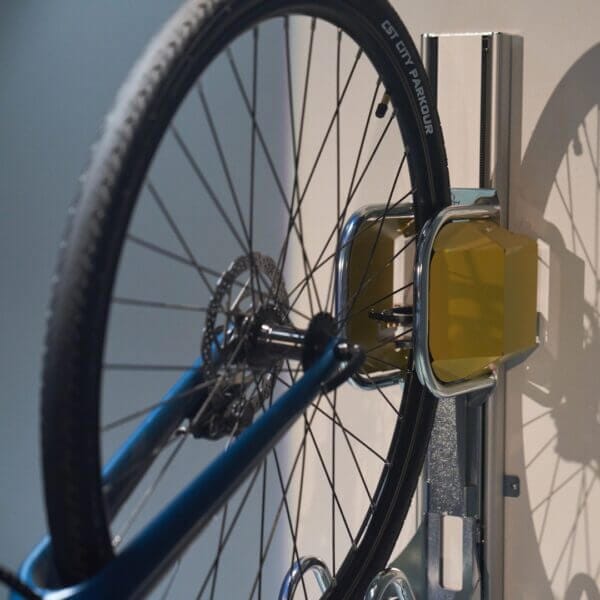 detail-van-ophangsysteem-fietsenrek Fietsenrek verticaal met wiel in gele houder aan de muur