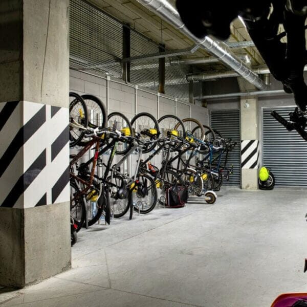 inpandige-fietsopslag-voor-openbare-ruimtes Fietsenrek aan muur in parkeergarage met meerdere fietsen