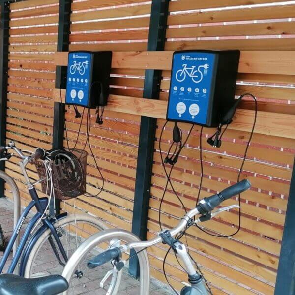 E-bike laadstation met wandmontage, voorzien van meerdere laadkabels voor elektrische fietsen.