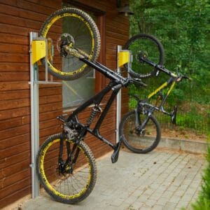 Verticaal fietsenrek met lift en muurbevestiging, gemonteerd aan houten wand met mountainbikes