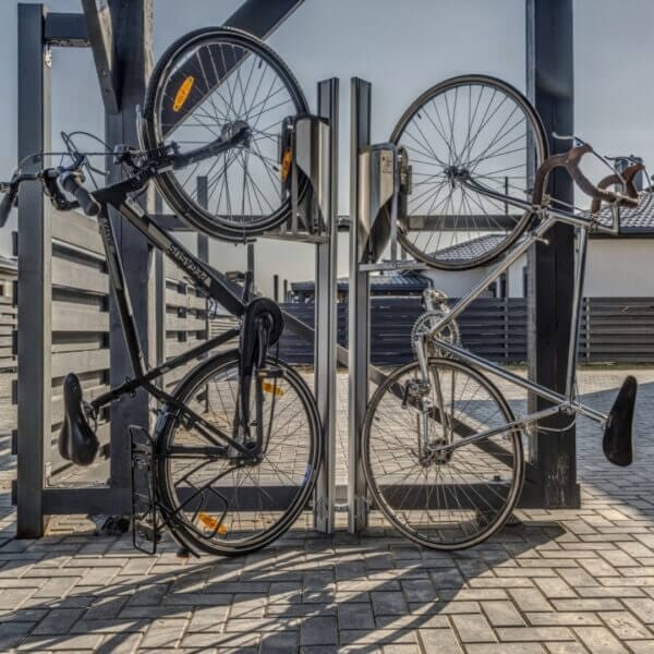 verticaal-fietsenrek-in-rijwieloverkapping Twee fietsen in verticale fietsenrekken met muurbevestiging buiten
