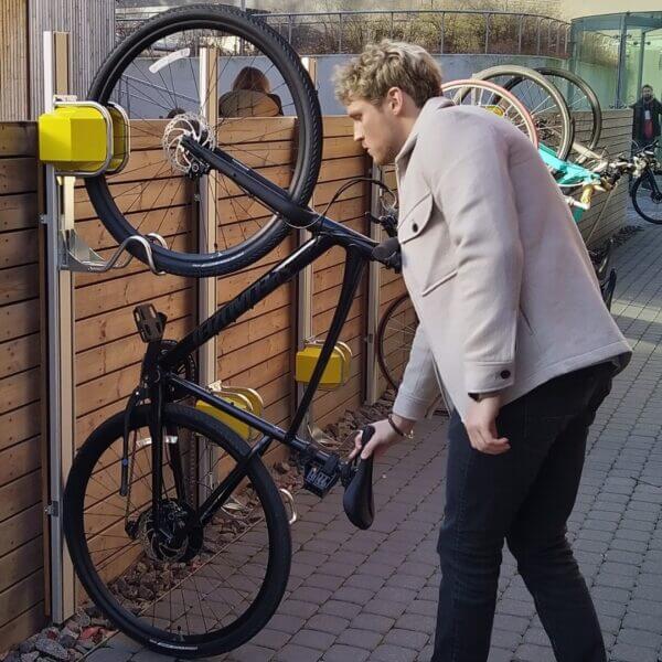 verticaal-fietsparkeer-systeem-heavy-umfeldt Fietsenrek aan de muur met verticale fiets en gebruiker