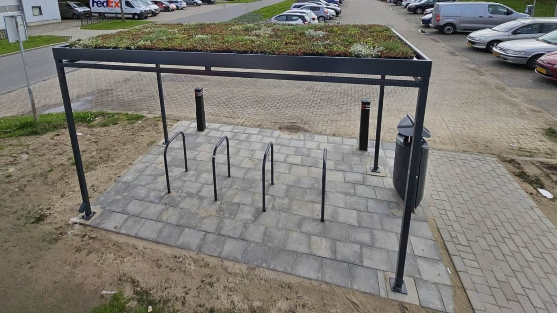 Fietsoverkapping met sedumdak, voorzien van fietsaanleunbeugels bij een parkeerterrein