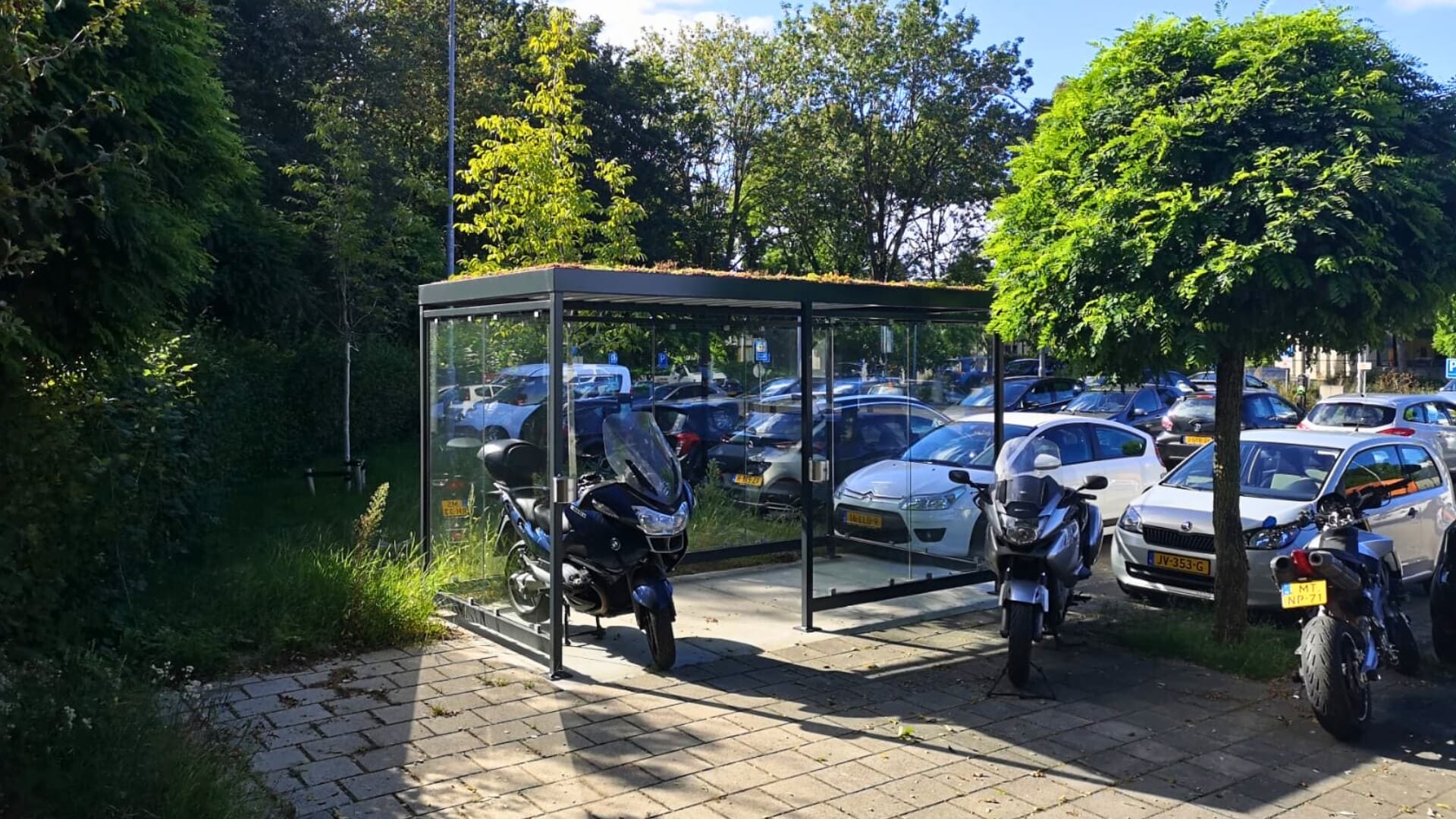 Fietsoverkapping en rookabri met sedumdak bij parkeerterrein met glazen wanden en groene dakbedekking