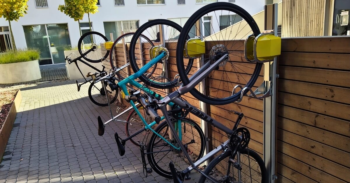Verticaal fietsenrek voor buitenruimte met meerdere fietsen verticaal geparkeerd tegen houten wand