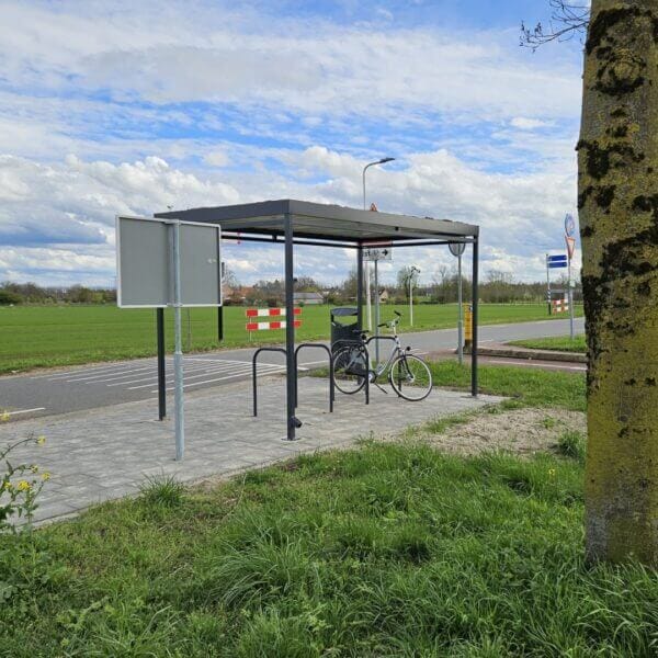 fietsoverkapping voor carpool kopen Fietsoverkapping met fietsnietjes langs een fietspad in een groen buitengebied met duidelijke bewegwijzering.
