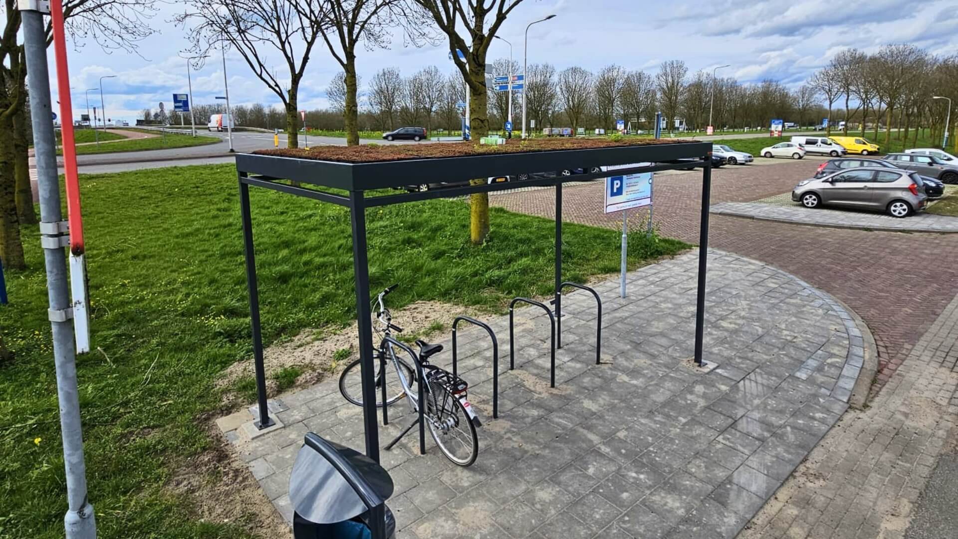 Duurzame rijwieloverkapping van staal met sedumdak en geïntegreerde fietsenrekken. Ideaal voor milieuvriendelijke en functionele buitenoplossingen.