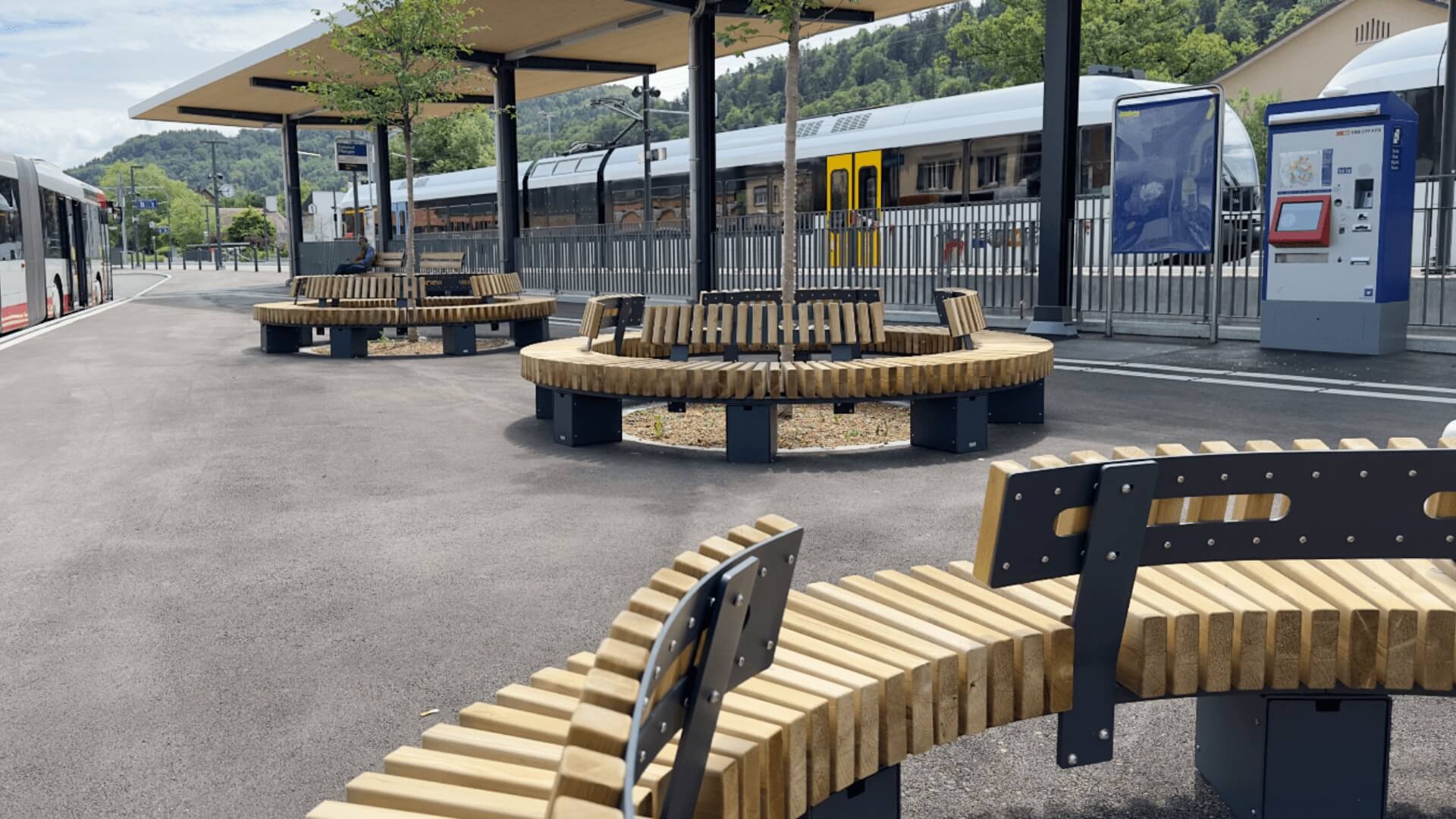 Ronde buitenbanken van staal en hout bij openbaar vervoersplein, duurzaam straatmeubilair in openbare ruimte