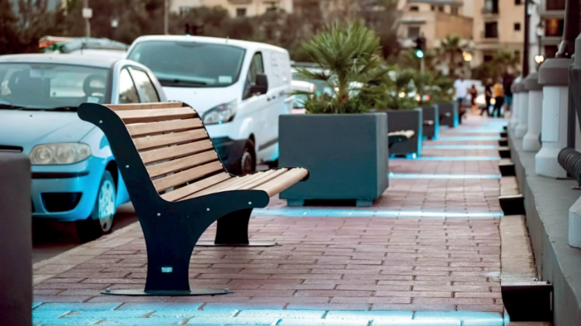 Houten straatbank met een ergonomisch ontwerp en zwart stalen onderstel, als straatmeubilair voor de openbare ruimte.