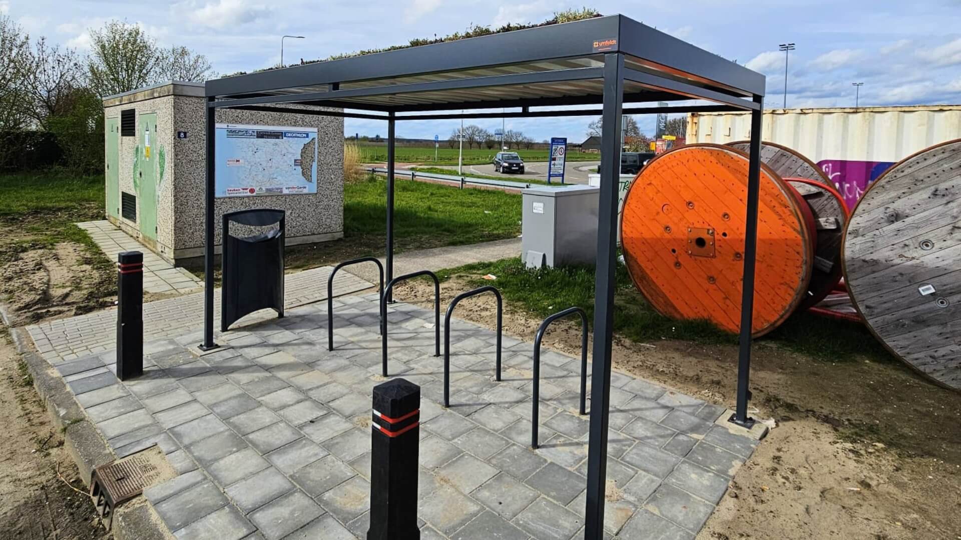 Duurzame fietsoverkapping met sedumdak en geïntegreerde fietsrekken, stevig verankerd op betonpoeren voor stabiliteit en lange levensduur.