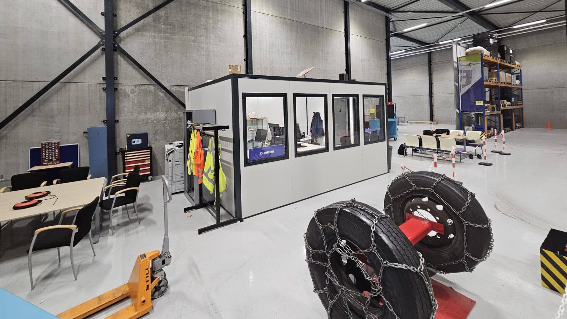 Modulair opgebouwde kantoorunit met glaswanden in een fabriekshal.