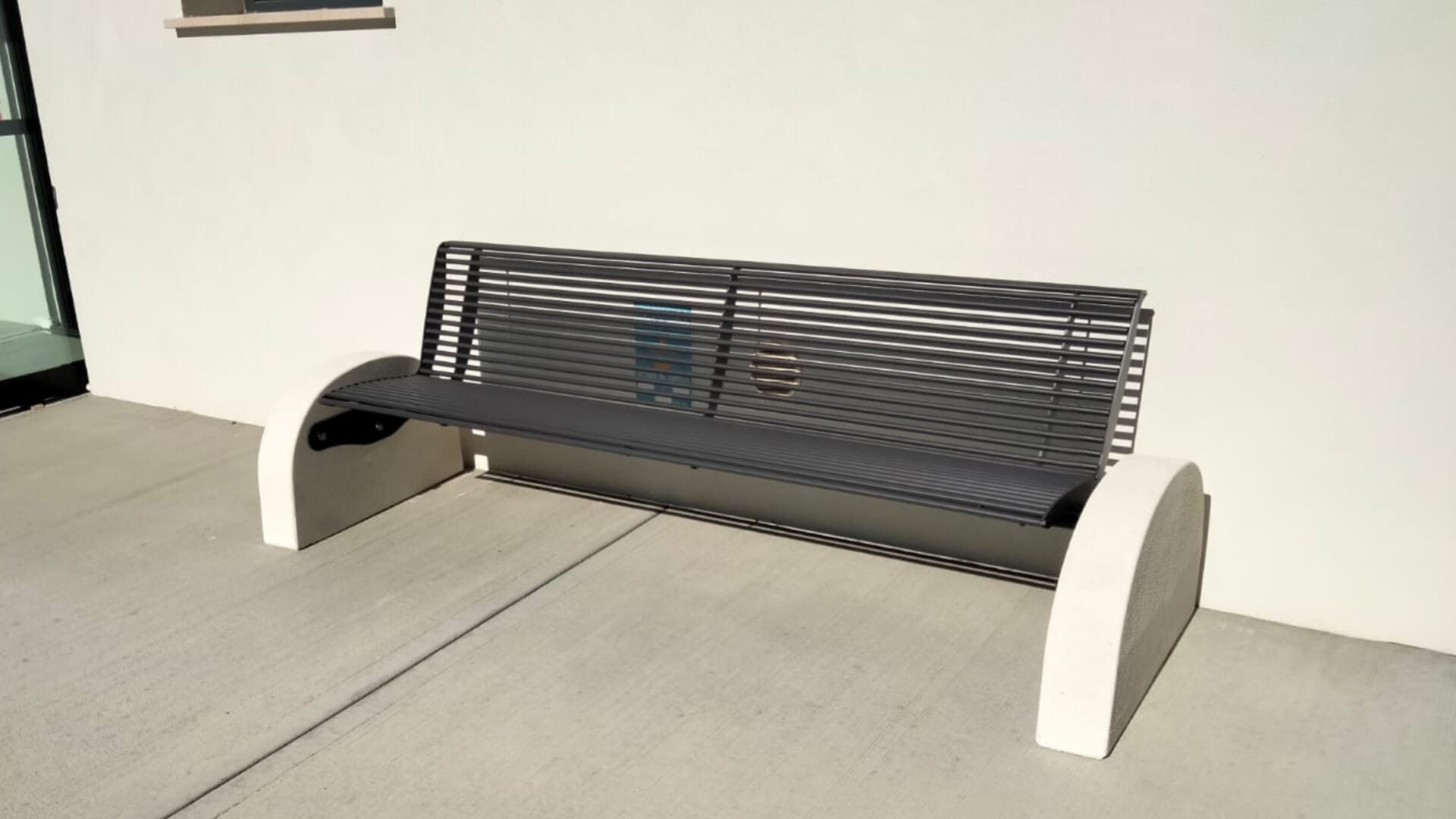 Moderne metalen parkbank voor openbare ruimte met stalen zitting en betonnen zijpanelen, geschikt als duurzame buitenbank.