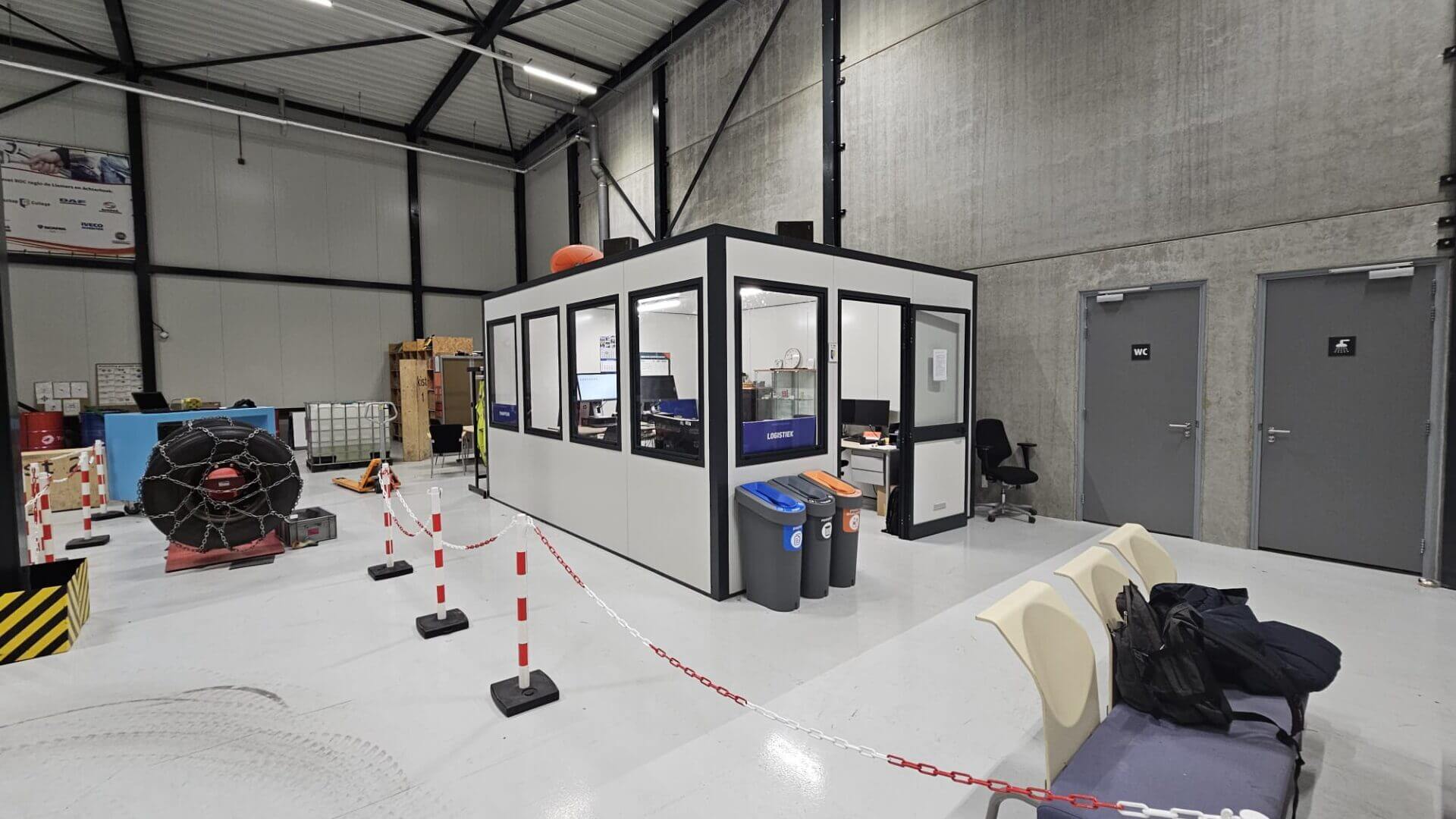 Modulaire kantoorunit in een magazijnomgeving met bureaus en werkplekken.