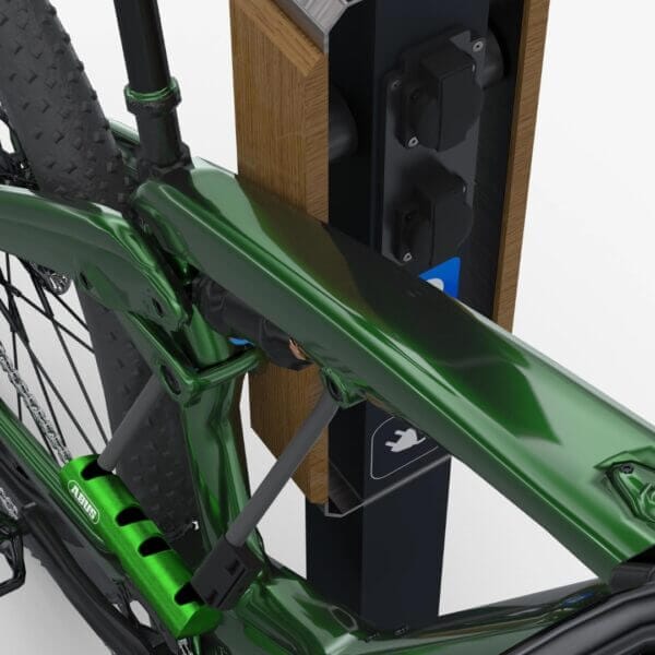 Stijlvolle design laadpaal voor e-bikes met geïntegreerde oplaadpunten. Van staal en met houten elementen waar een groene fiets tegenaan staat.