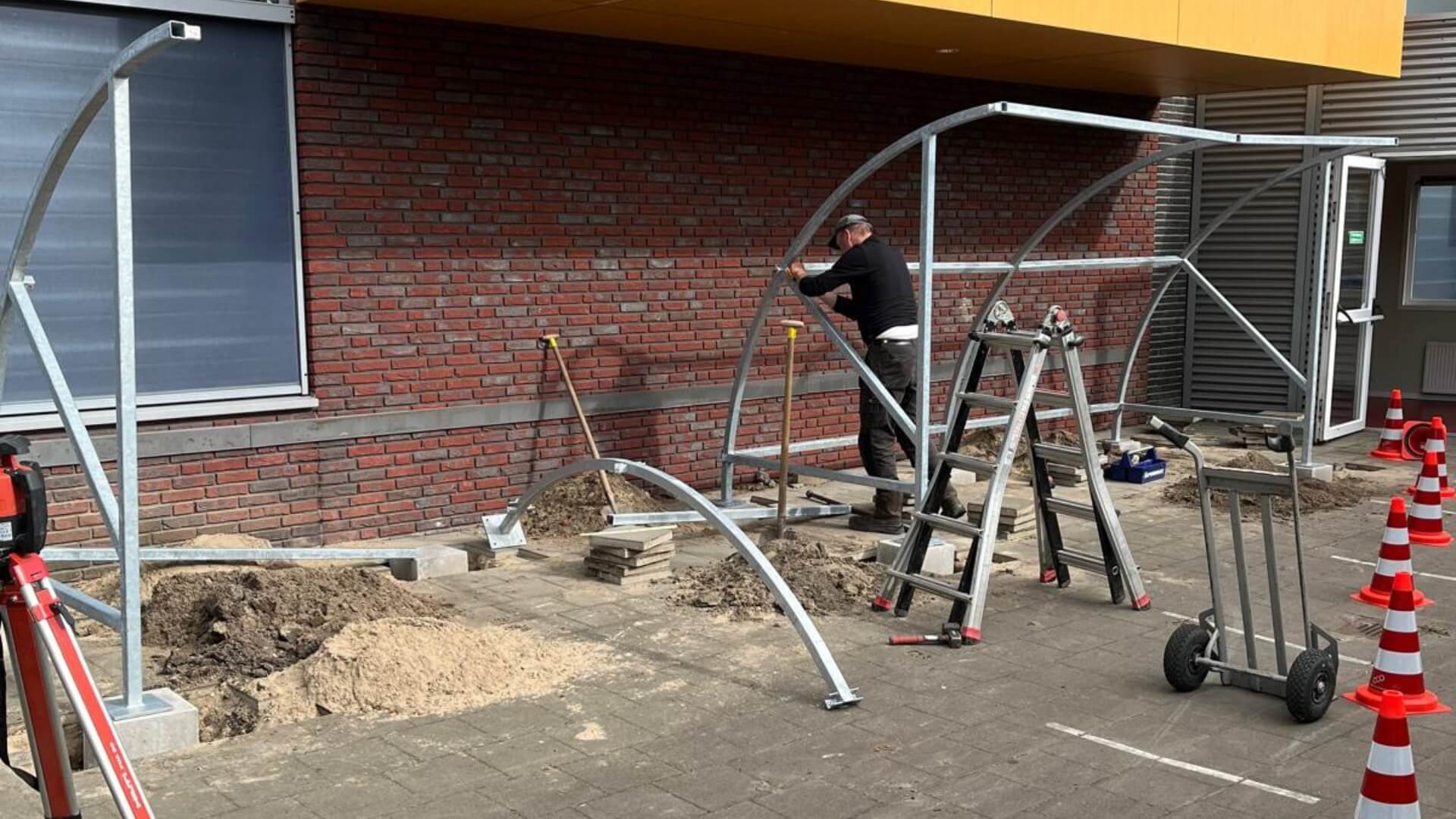 Montage van fietsoverkapping inclusief plaatsing bij school in Oirschot met stalen boogconstructie op betonpoeren