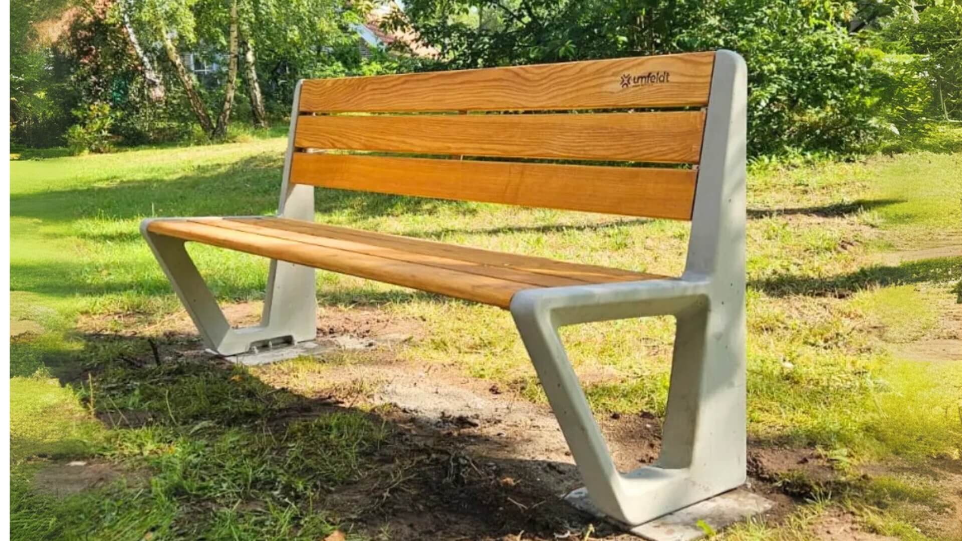 Parkbank met betonvoet en houten zit- en rugleuning, geplaatst in een groene parkachtige omgeving.