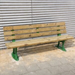 Parkbank met stalen frame en houten latten voor de openbare ruimte, geplaatst tegen een muur bij een bedrijfspand.