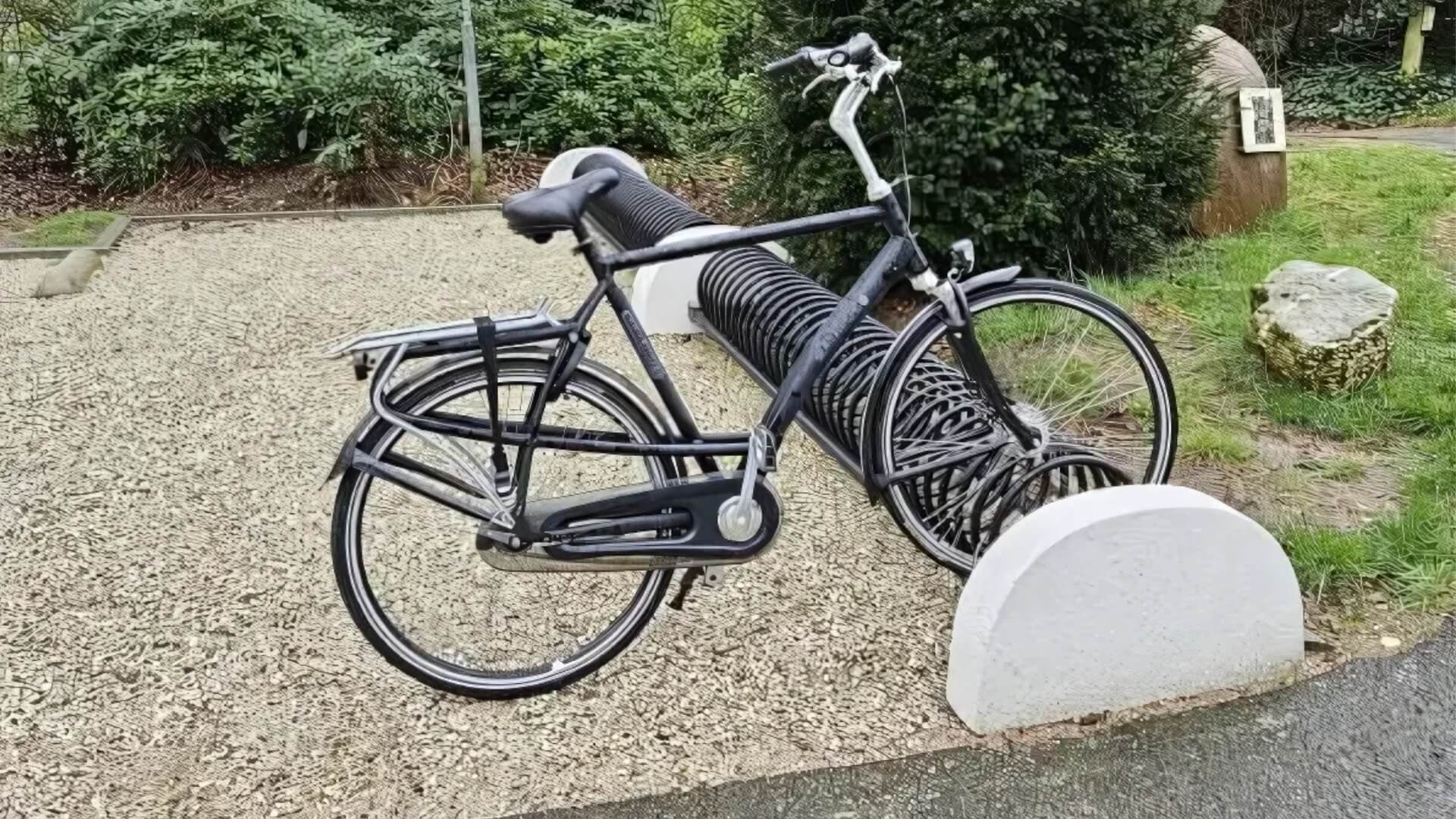 Rond buizen fietsenrek in spiraalvorm met betonnen voeten en een gestalde fiets
