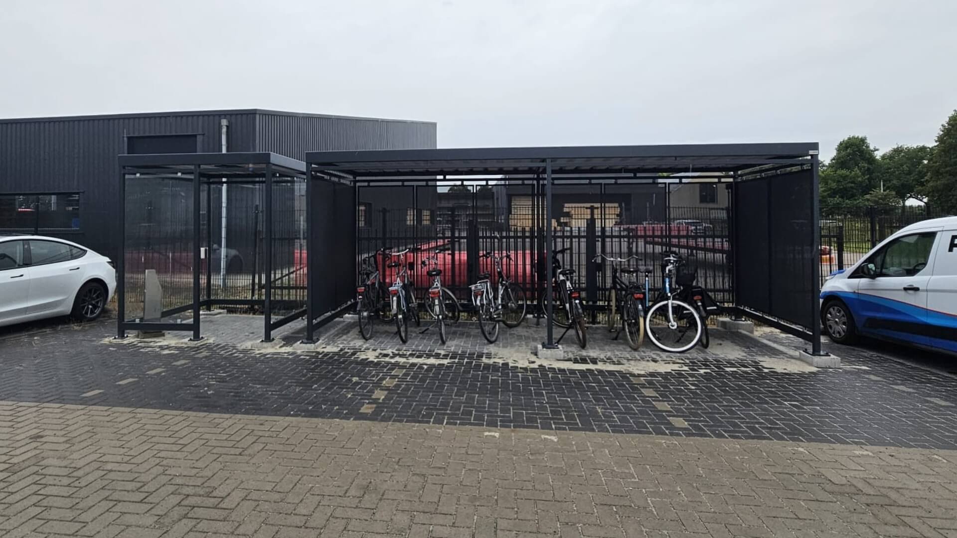 Rookabri voor buiten met stalen constructie en glazen wanden naast fietsoverkapping met fietsenstalling