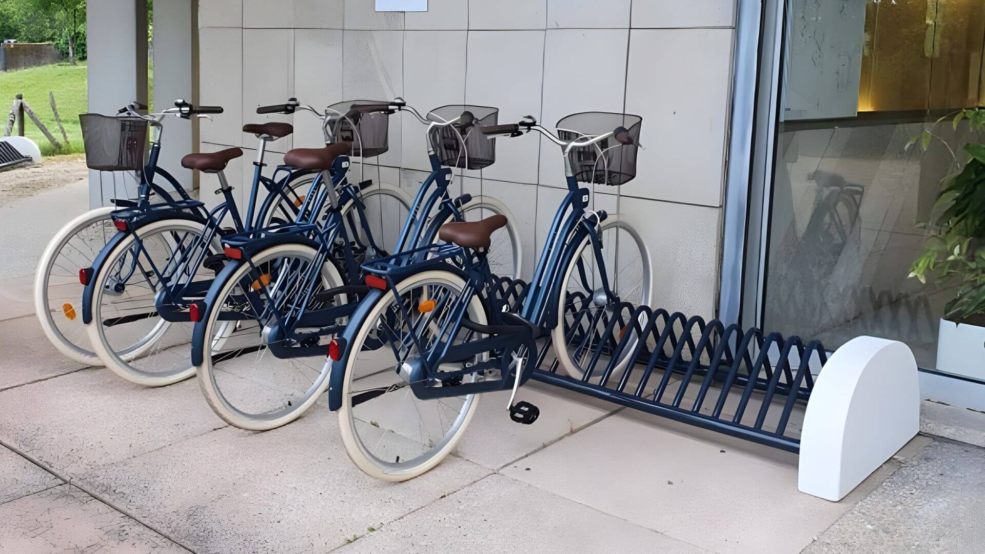 Fietsenrek voor bedrijven en instellingen, geplaatst bij een entree met vier stadsfietsen.