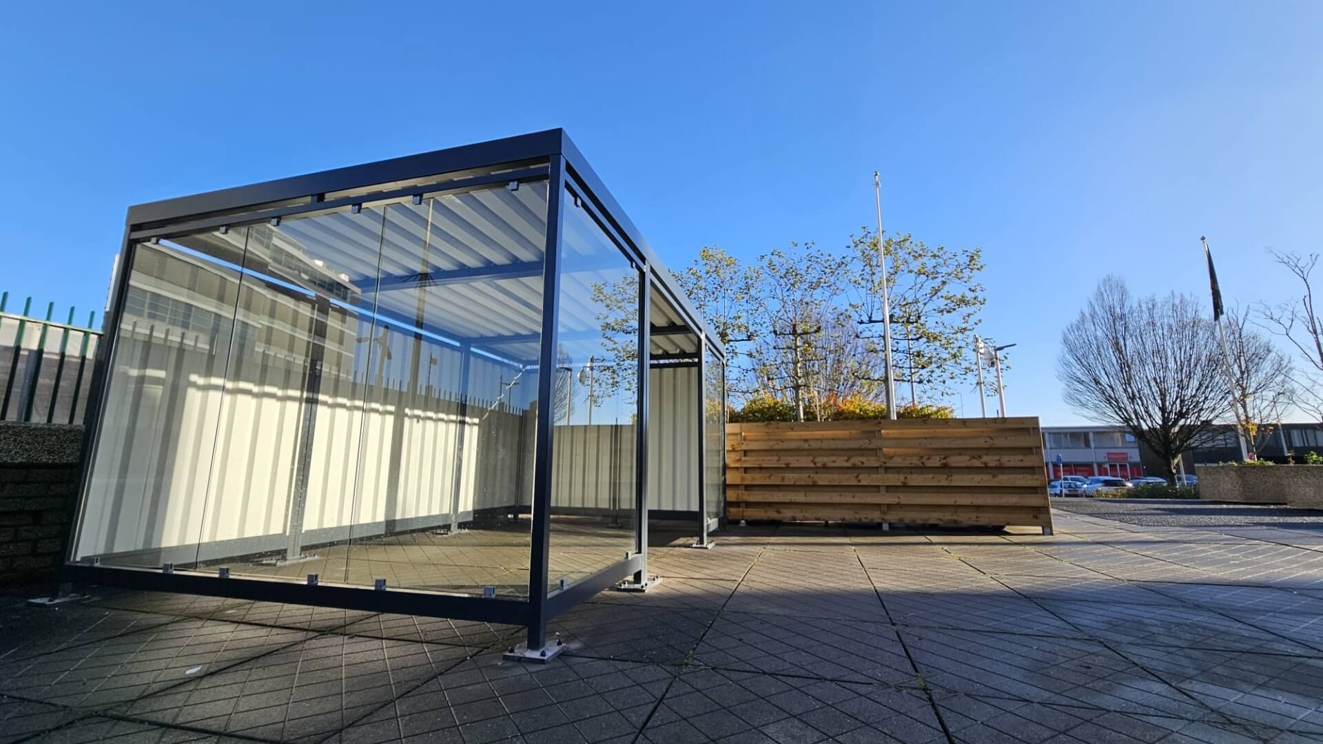 Maatwerk rookoverkapping met volledig transparante ESG-glaswanden en stalen frame, geplaatst op het buitenterrein bij COA Amsterdam