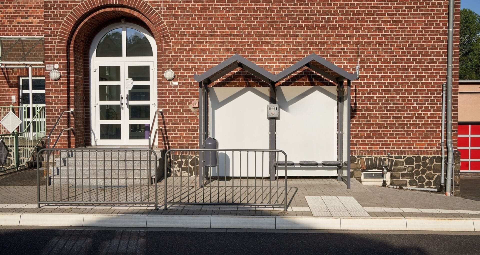 Compacte rookhok tegen een bakstenen gebouw met zitbank en beschutte wanden