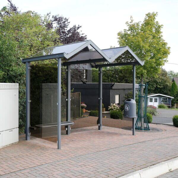 Rookhok voor bezoekers en medewerkers direct aanschaffen Moderne rookoverkapping met glazen wanden en opvallend zigzag dak bij een straat in een woonomgeving