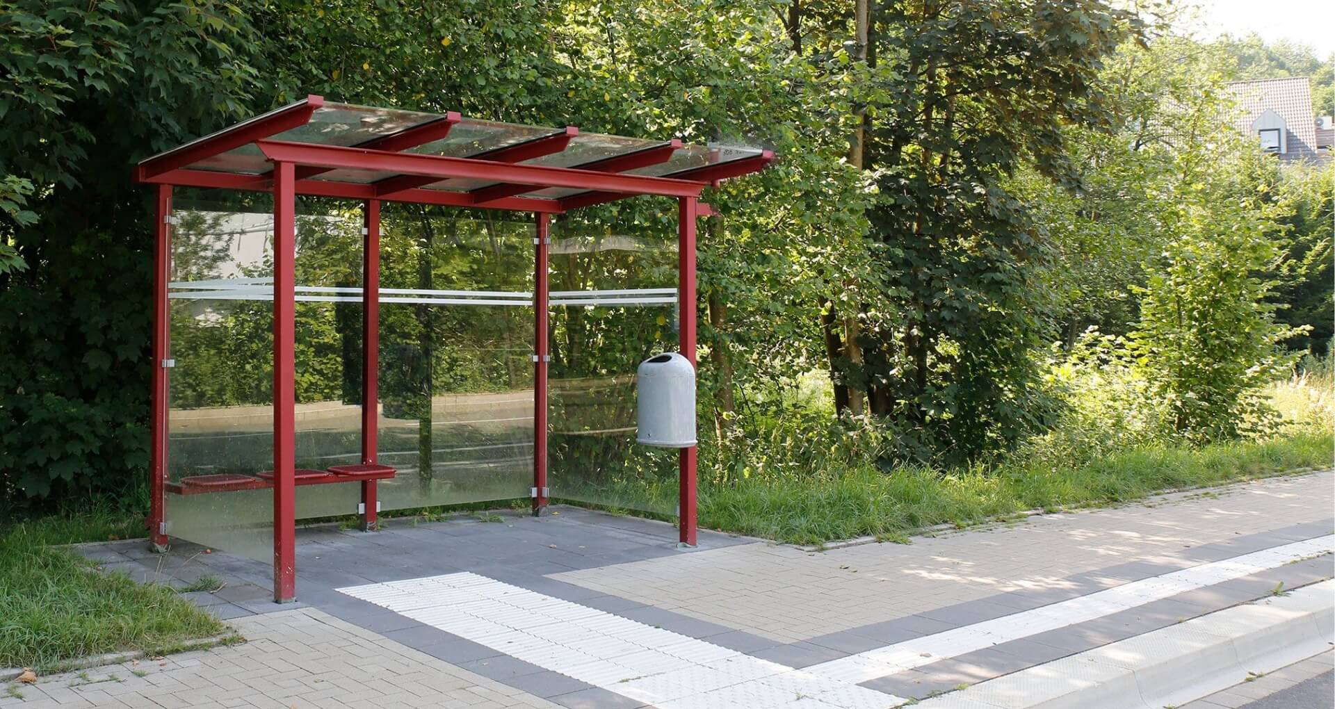 Rode rookcabine met glazen wanden langs een weg, geschikt als bushalte of rookruimte